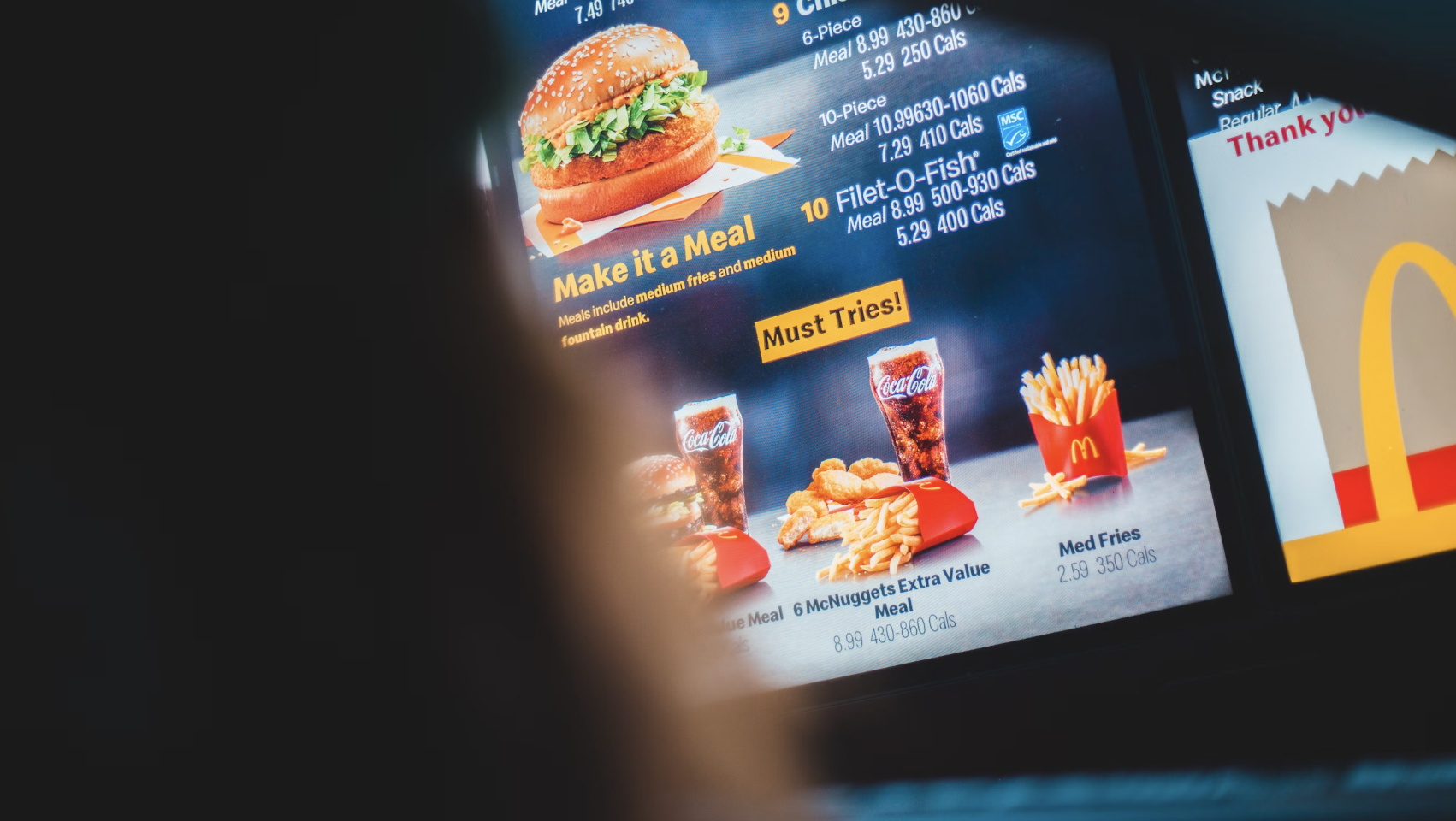 McDonald's digital menu showing a burger, fries, Coca-Cola, and McNuggets meal with pricing and calorie information